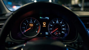Vue réaliste du tableau de bord d’une voiture de nuit avec un voyant moteur allumé, ambiance pédagogique et éclairage bleu doux.