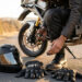 Moto garée au bord de la route avec casque et gants posés, vérification visuelle avant le départ.