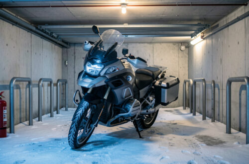 Moto stationnée et sécurisée dans un garage collectif pendant l’hiver, avec dispositifs de protection contre le vol et l’incendie.