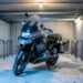 Moto stationnée et sécurisée dans un garage collectif pendant l’hiver, avec dispositifs de protection contre le vol et l’incendie.